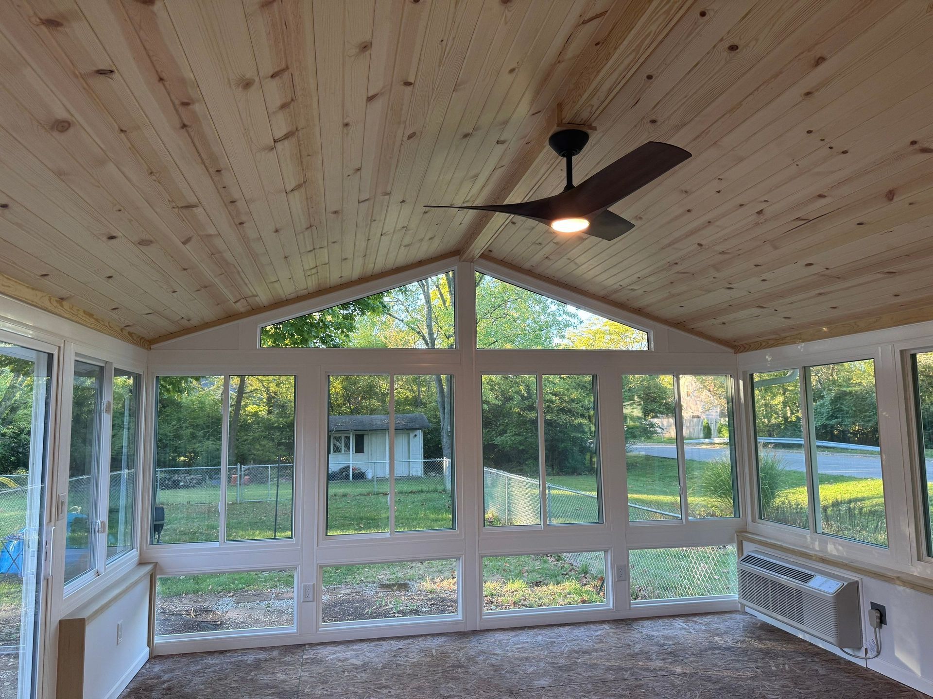 Screened porch with wood ceiling, ceiling fan, and large windows overlooking a grassy yard