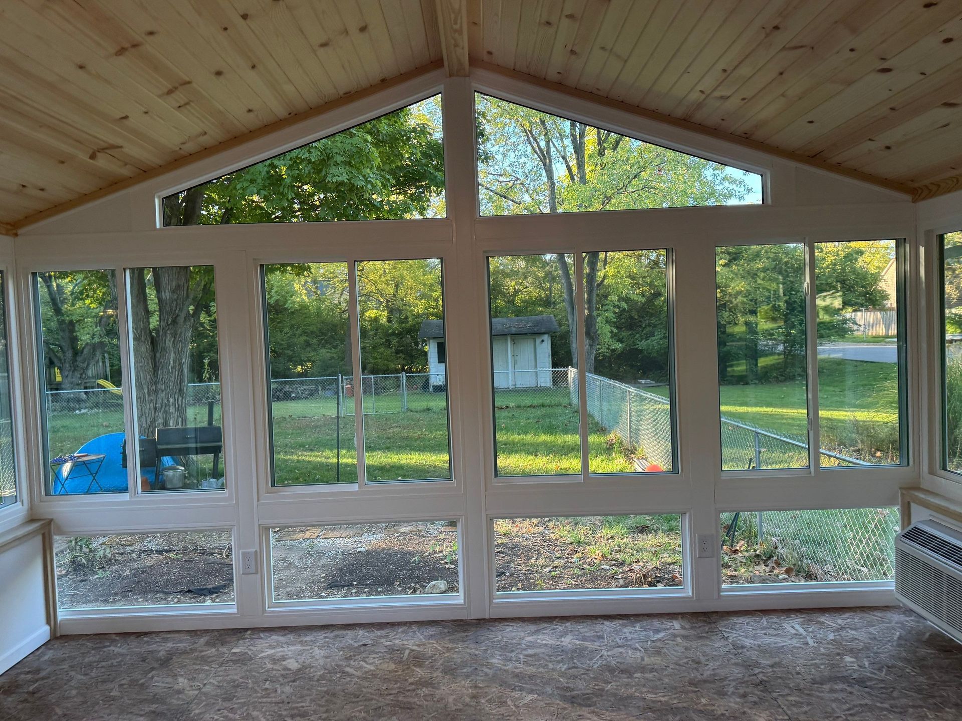 Wood-paneled room with large windows and a view of trees and a yard outside.