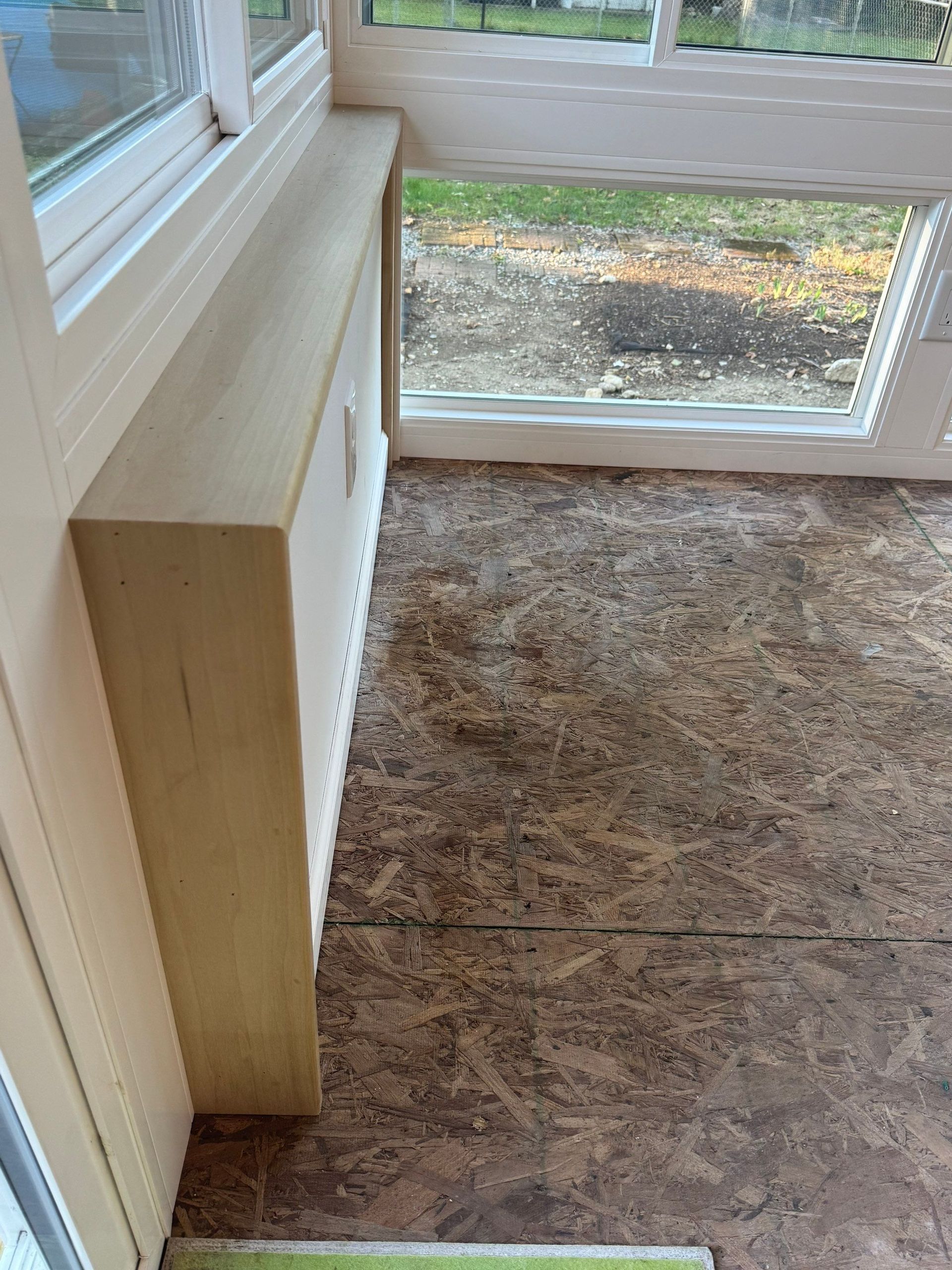 Small room with a window, beige cabinet, and worn brown carpet.