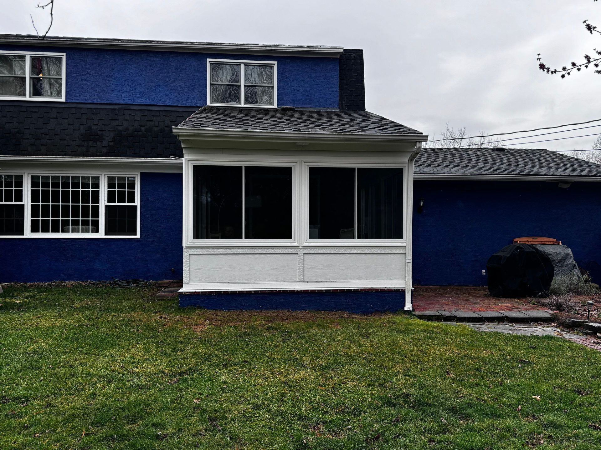 Blue two-story house with white porch and a grassy front yard