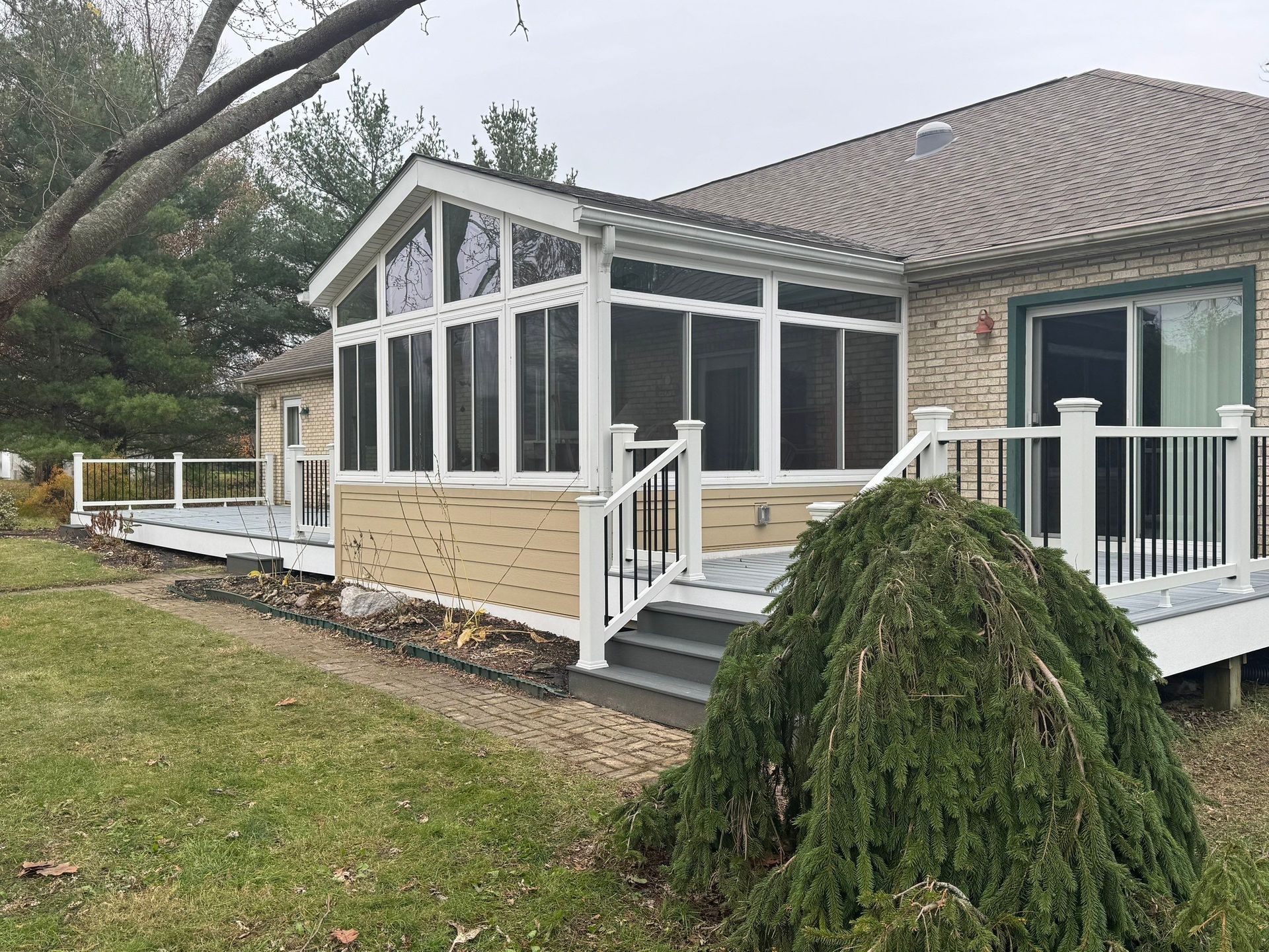Suburban house with a white screened porch and deck beside a grassy yard