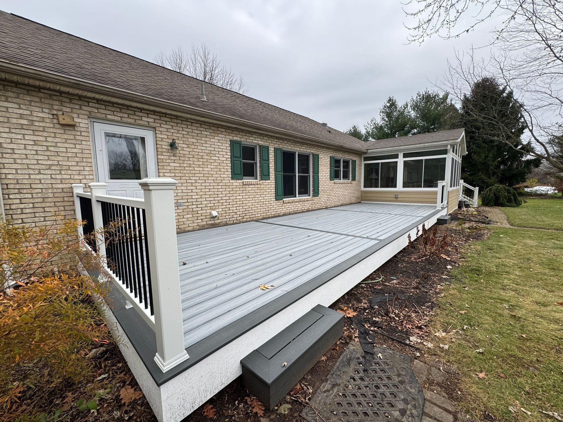 Front porch ramp with white railings attached to a brick house on a cloudy day