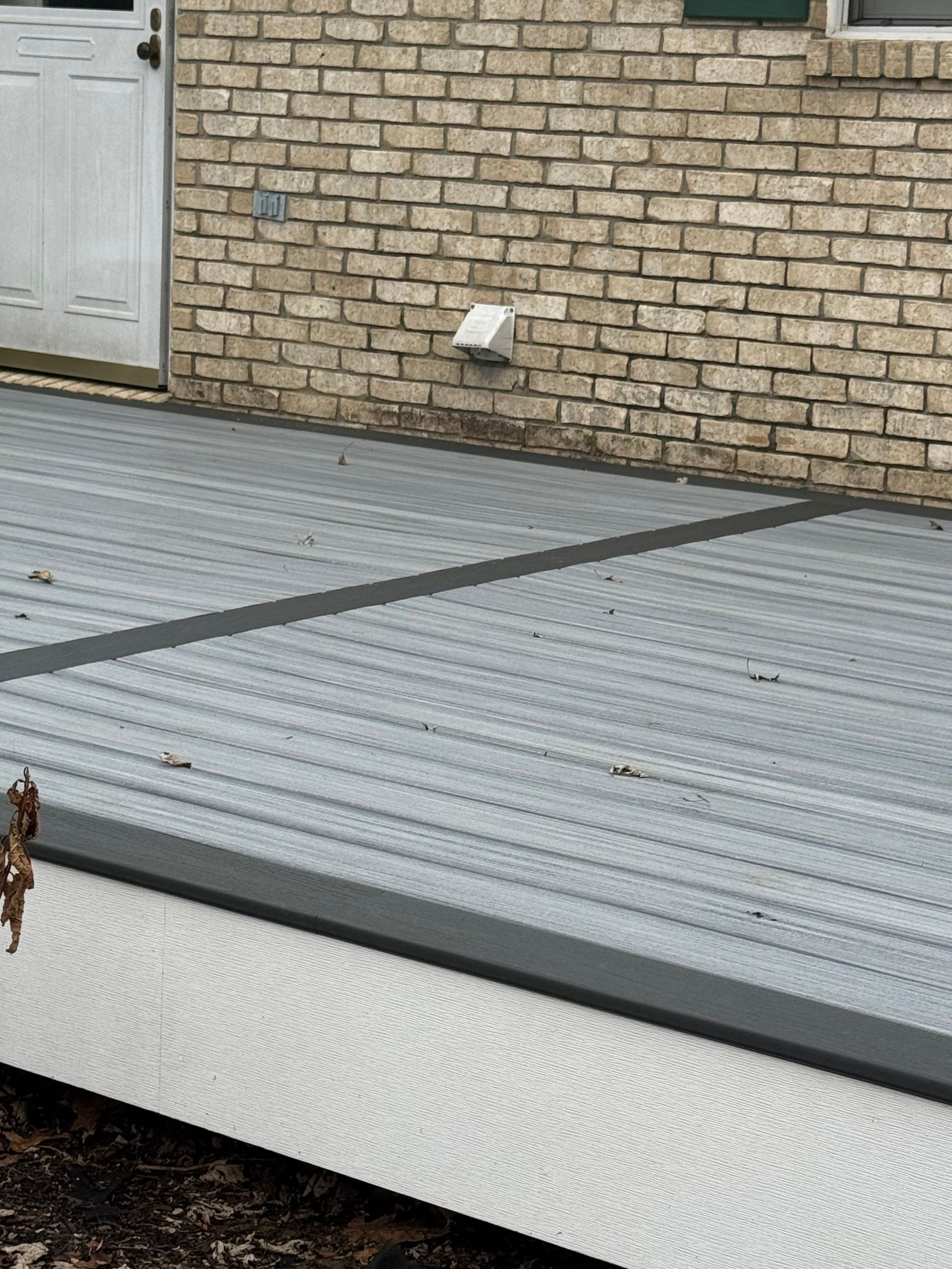 Corrugated metal roof beside a brick wall and white door, with a small vent or light fixture.