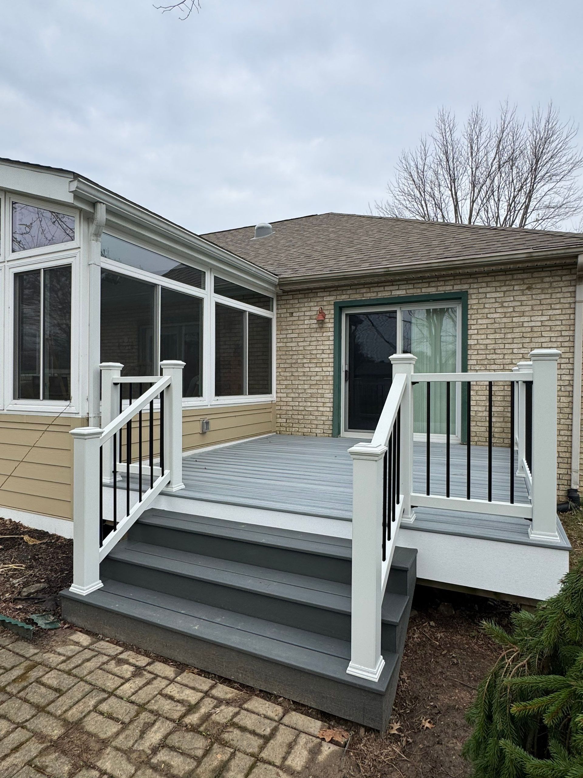 Back porch with gray stairs and white railings on a brick house