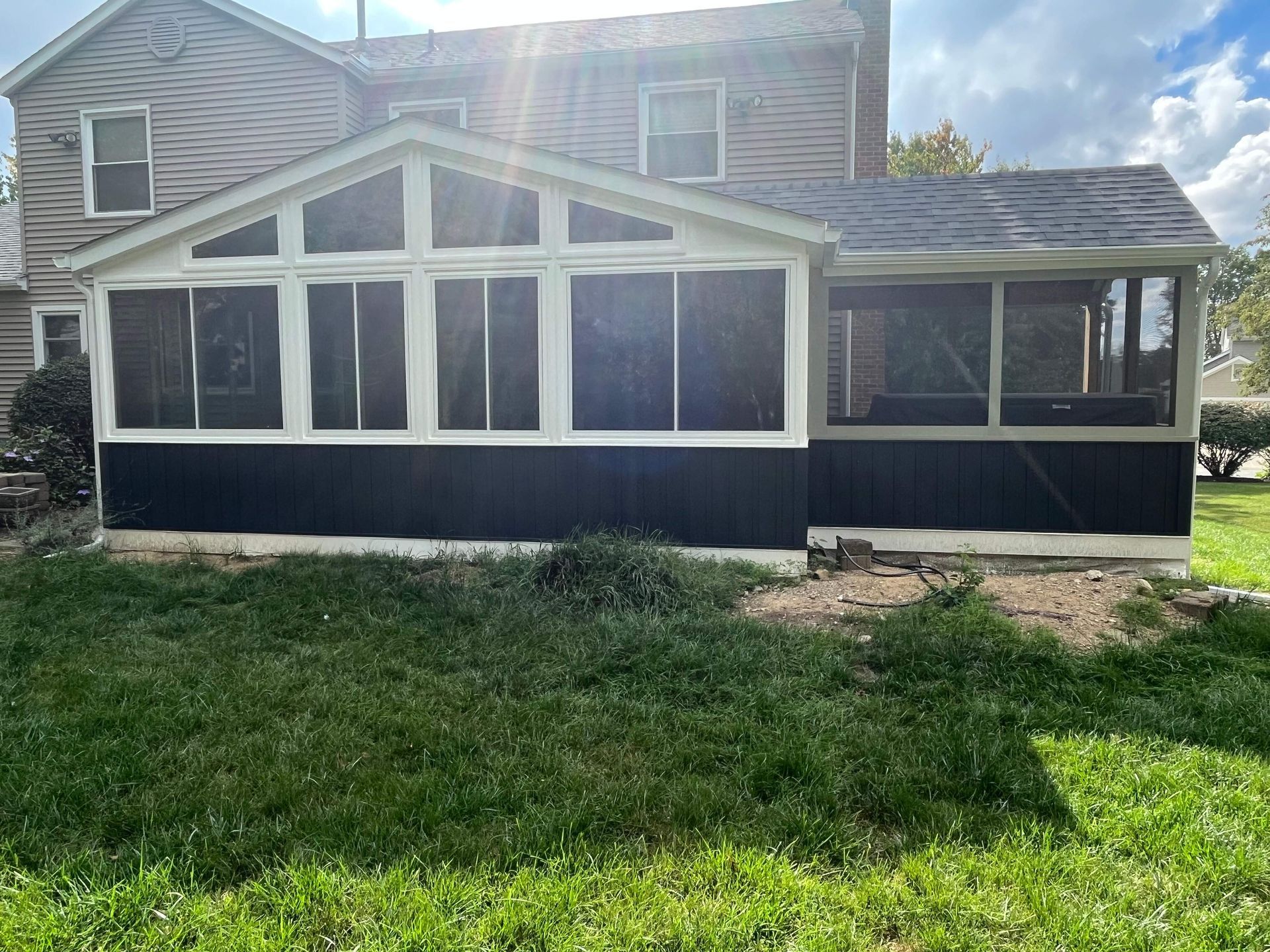 White house with a screened porch and grassy yard in front, viewed from outside