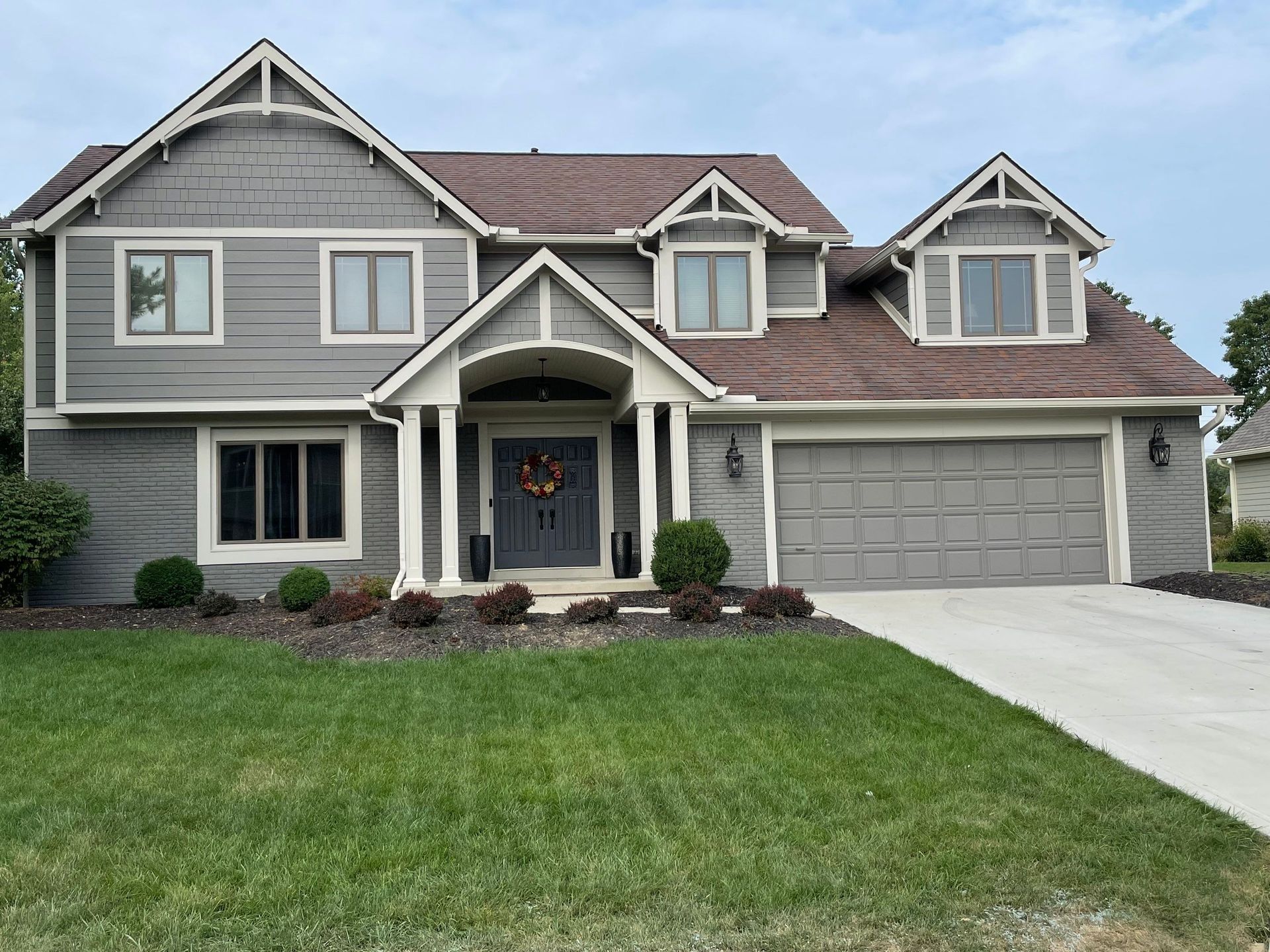 Gray suburban house with a front lawn, covered entry, and attached two-car garage