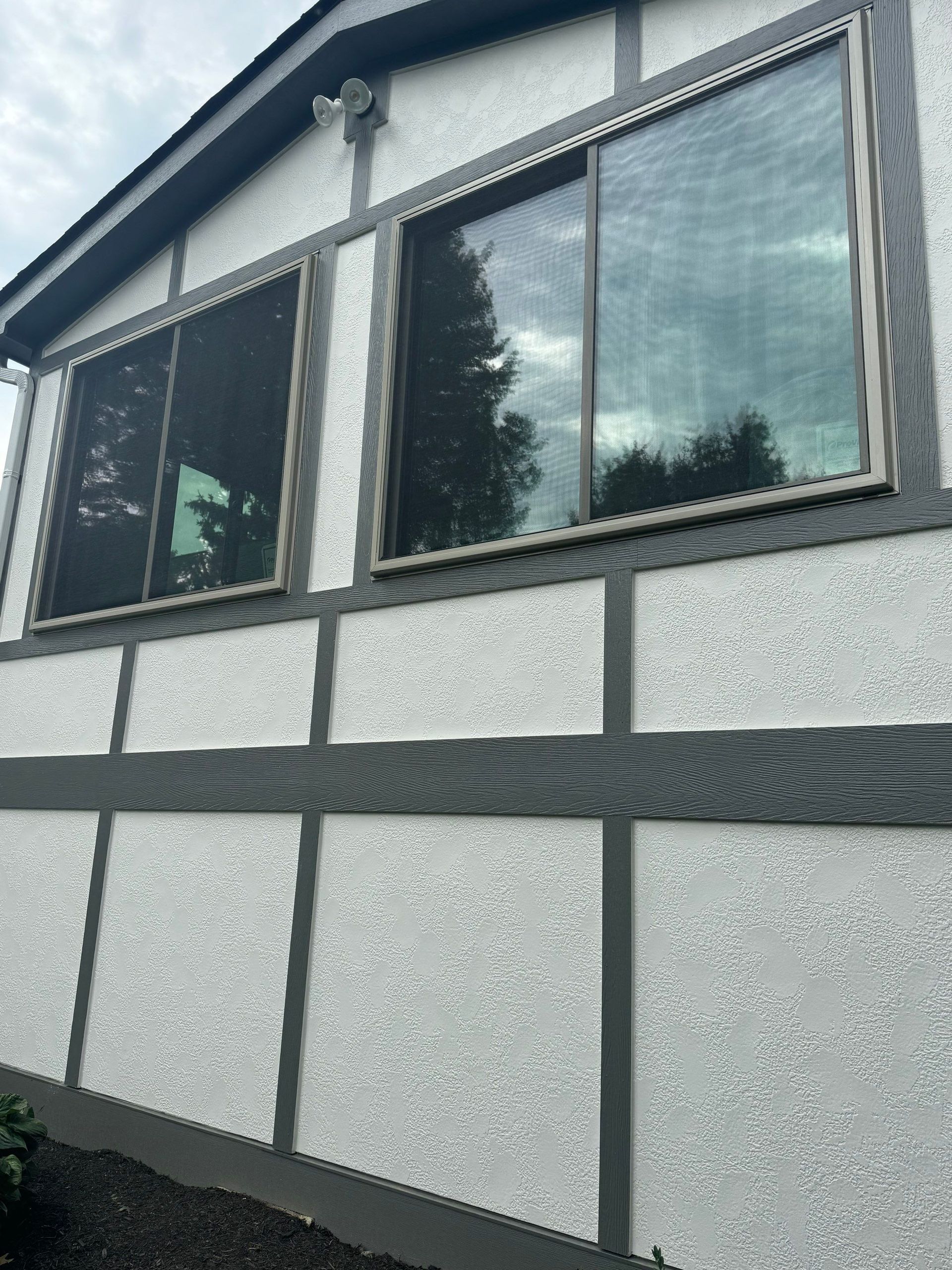 Exterior of a stucco house with dark trim and large reflective windows