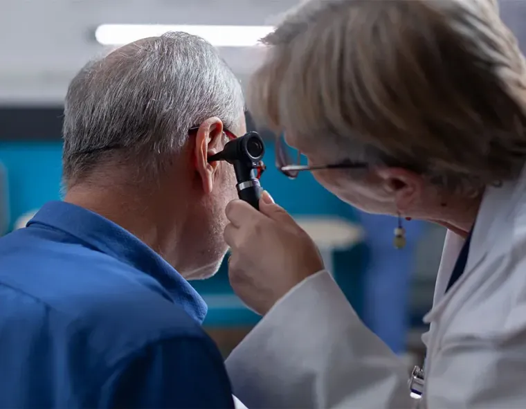 Doctor examining a patient’s ear with an otoscope in a clinic