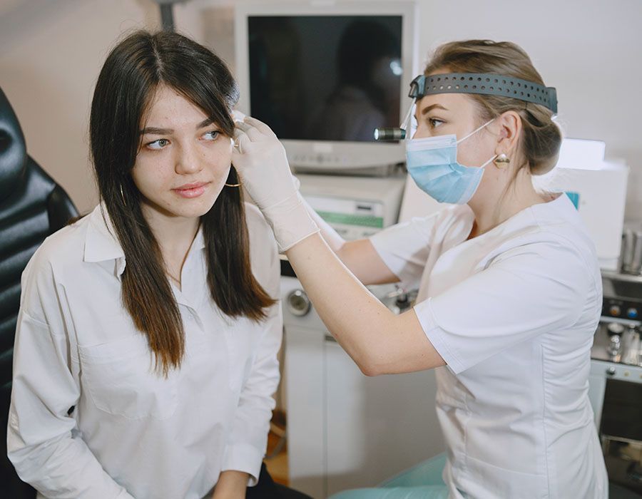 Clinician measuring a seated patient’s eye with a handheld device in a clinic room