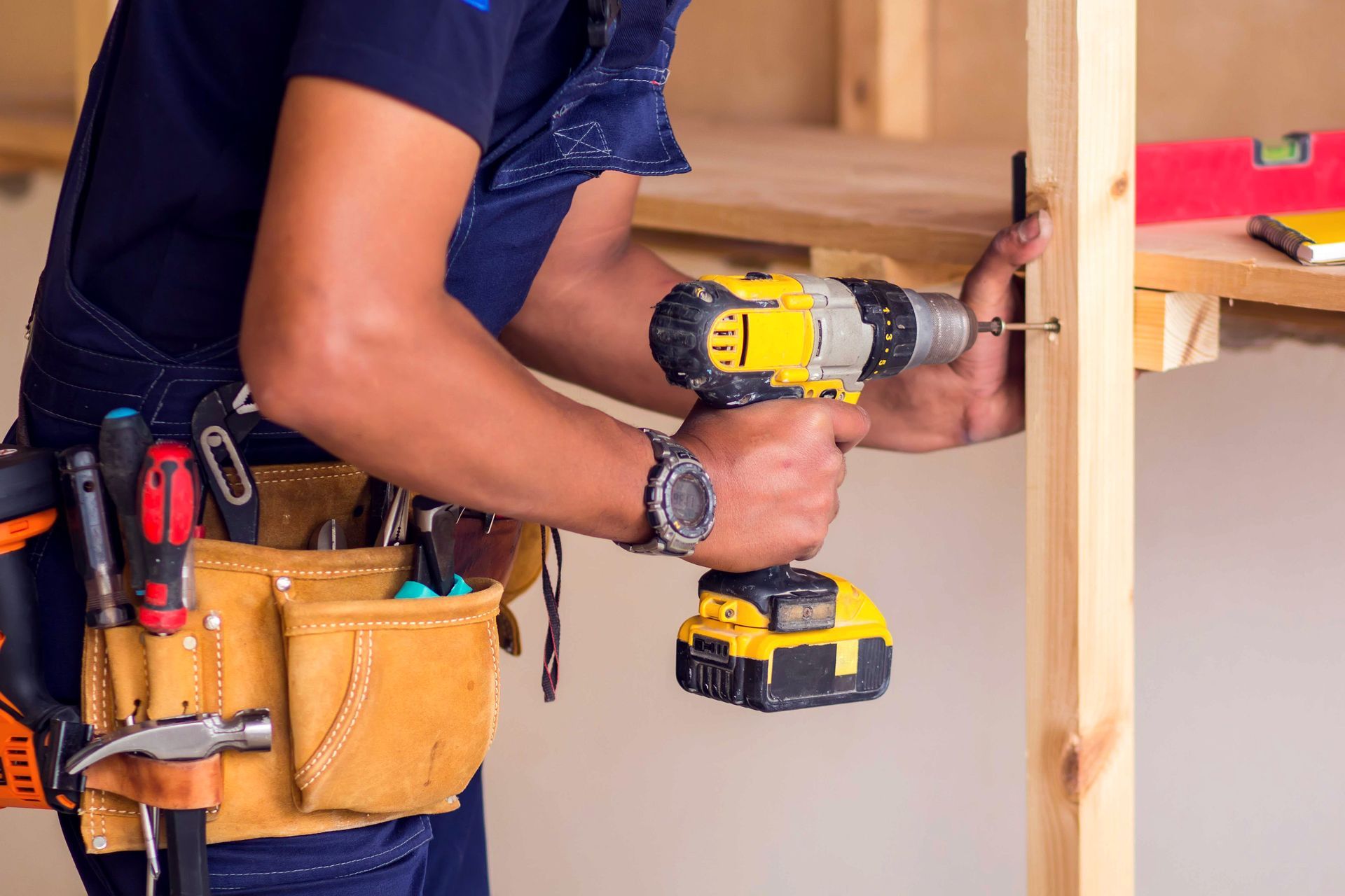 A man is using a drill on a piece of wood.