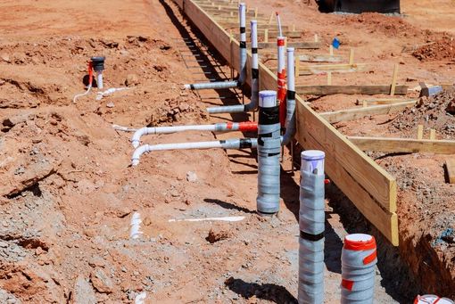 Utility trench with exposed pipes and workers at a construction site