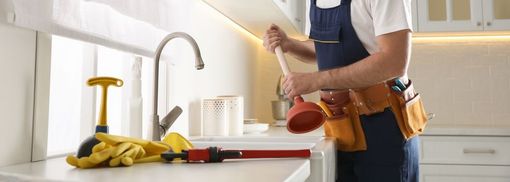 Person using a screwdriver to fix a cabinet in a bright kitchen, with tools on the counter