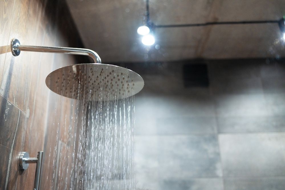Modern bathroom showerhead spraying water in a tiled shower stall