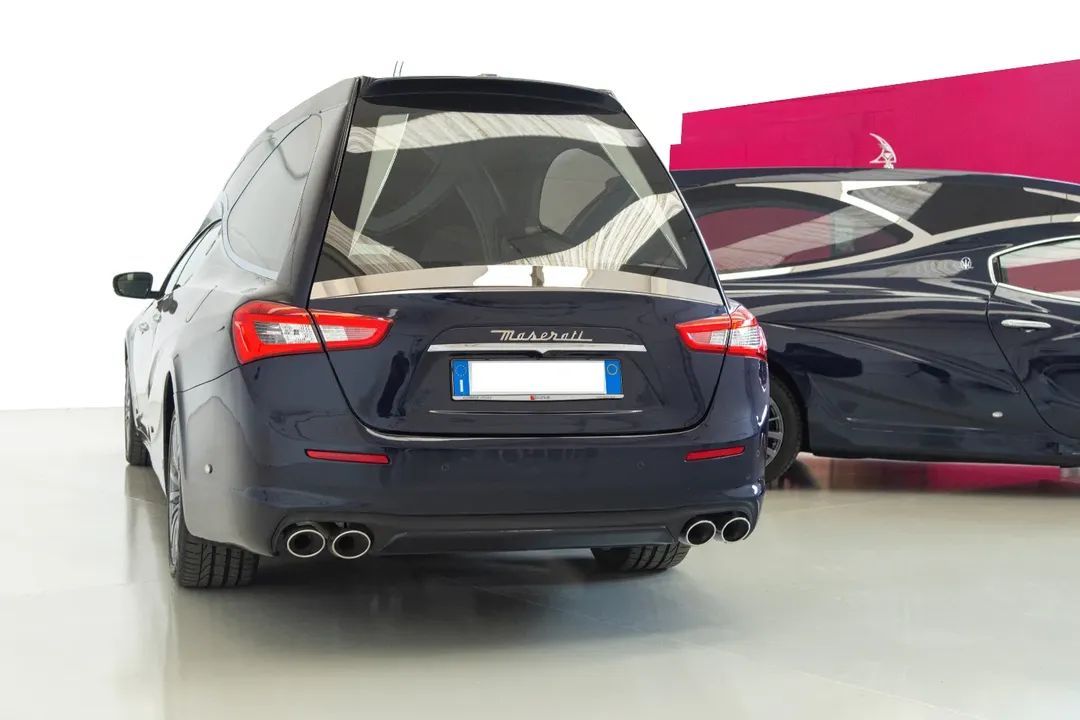 Due SUV scuri parcheggiati in uno showroom luminoso, vista posteriore di un SUV nero in primo piano.