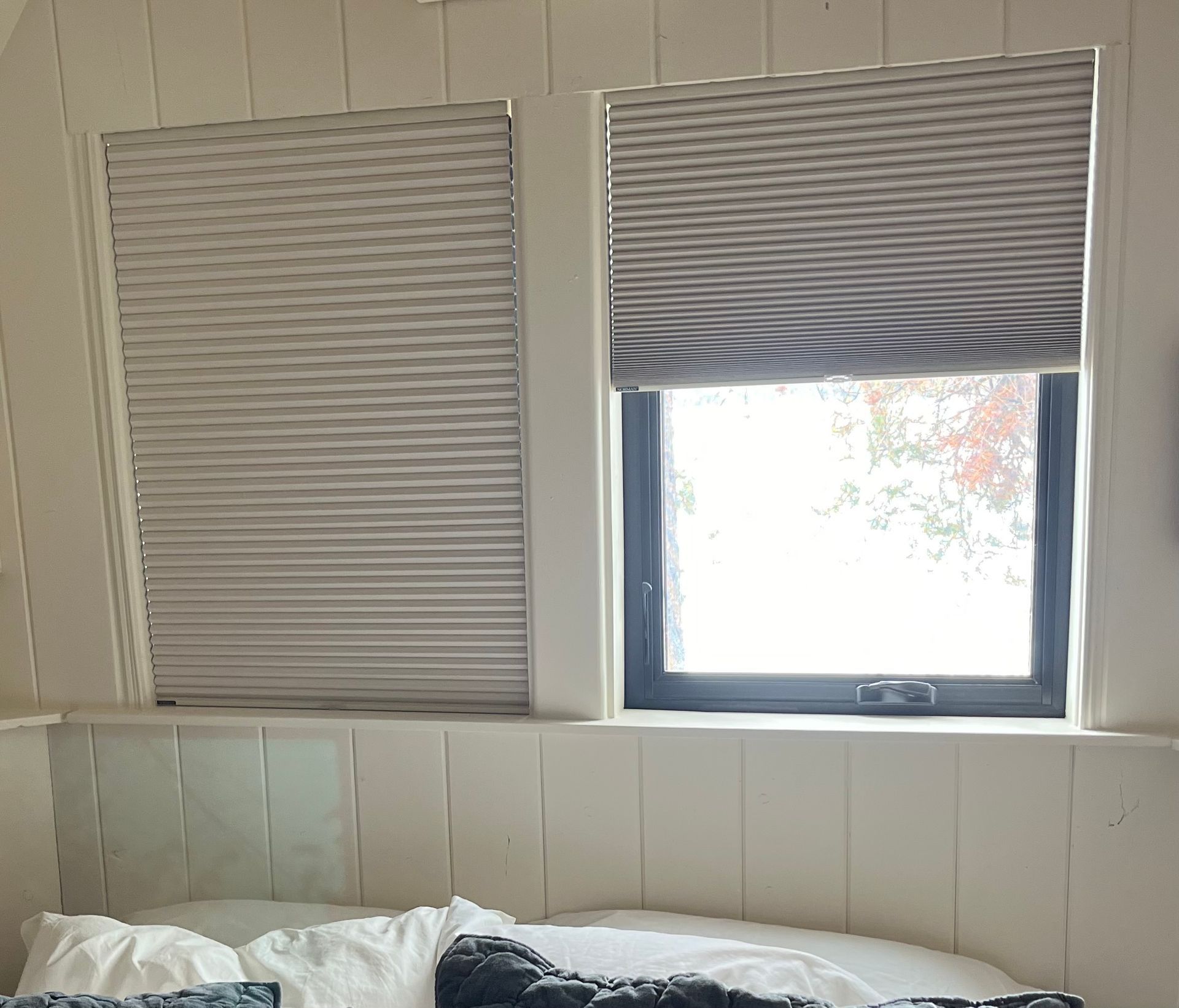 Four white plantation shutter panels covering a window, with top and bottom sections allowing for light adjustment.