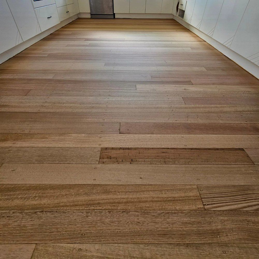 A Kitchen With a Wooden Floor and White Cabinets — ATM Floors In Mount Louisa, QLD