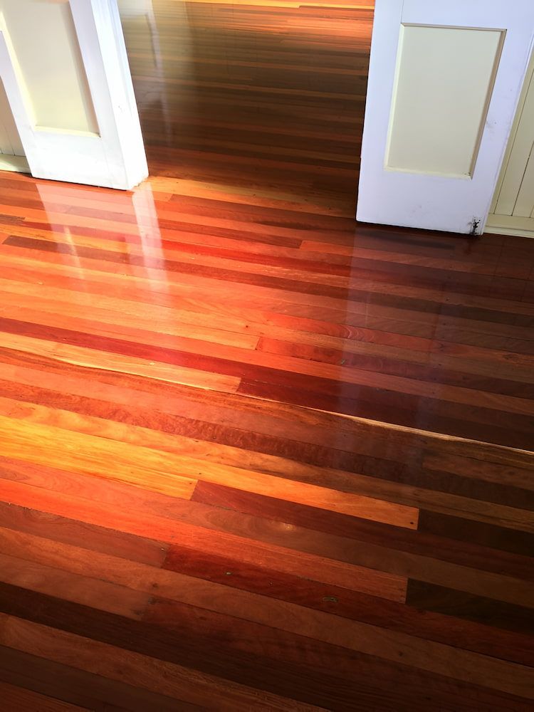An Empty Room With A Wooden Floor And Two Windows — ATM Floors In Mount Louisa, QLD A Wooden Floor With a Stencil of a Circle on It — ATM Floors In Mount Louisa, QLD