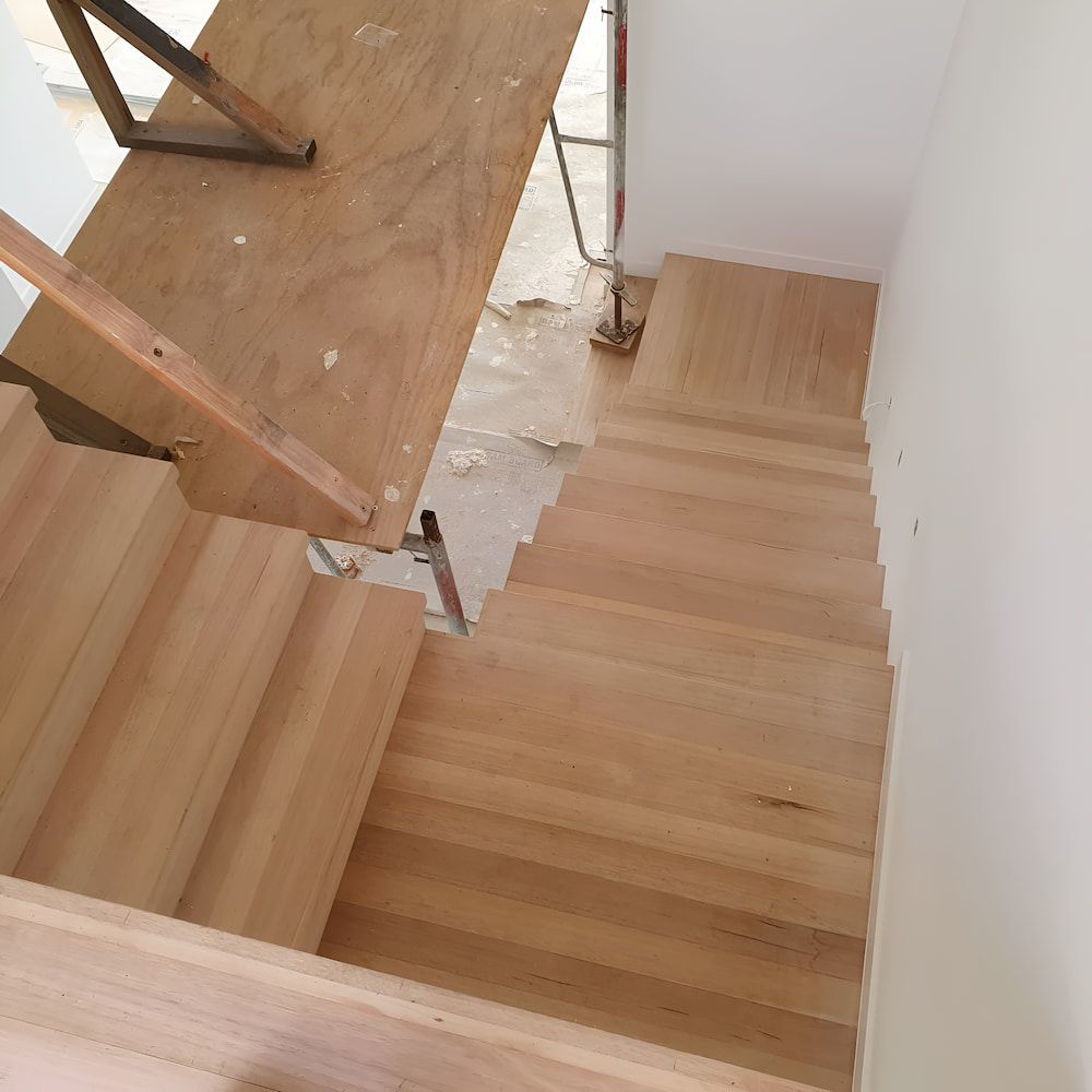 A Wooden Staircase With a Metal Railing is Under Construction — ATM Floors In Mount Louisa, QLD