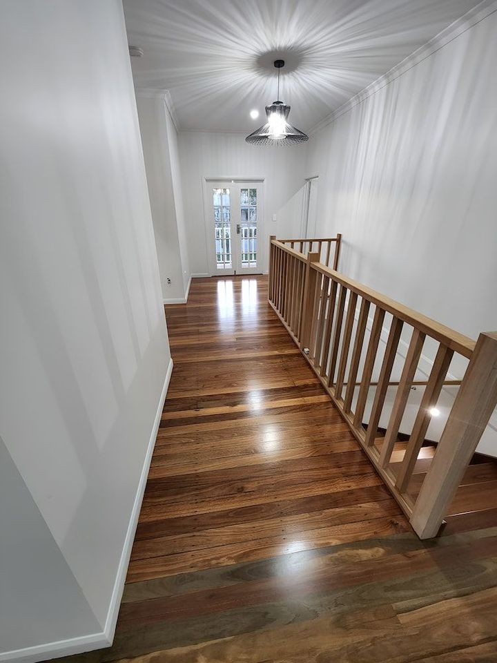 A Hallway With Wooden Floors and Stairs in a House — ATM Floors in Townsville, QLD