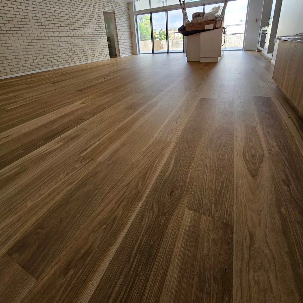 A Living Room With a Wooden Floor and a Brick Wall — ATM Floors In Mount Louisa, QLD