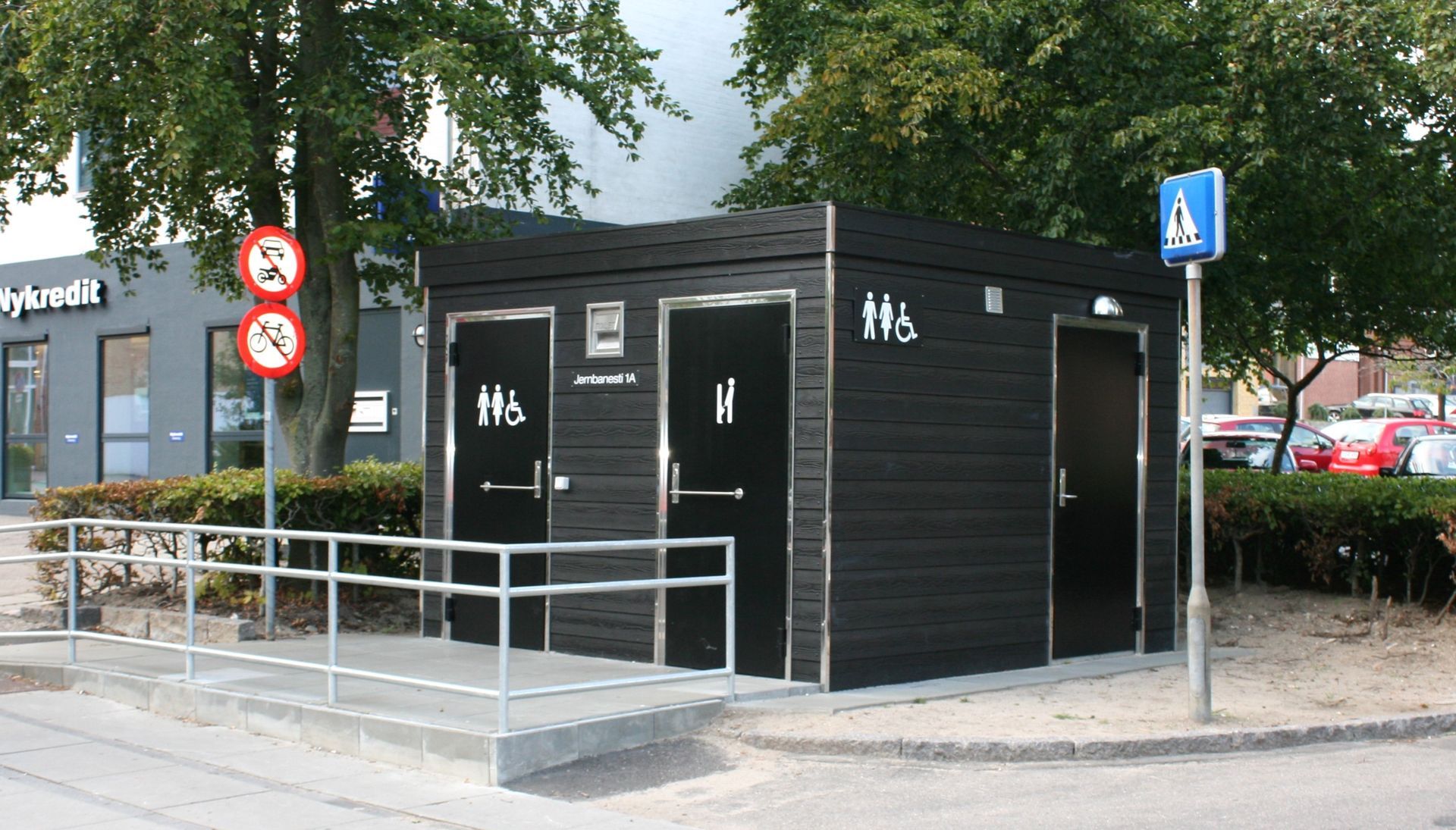En sort bygning med to toiletter og en handicaprampe