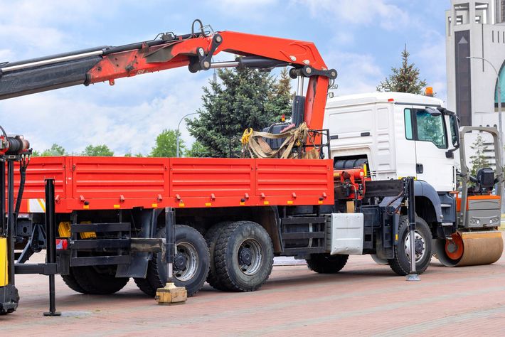 Un camion rosso con una gru attaccata è parcheggiato sul lato della strada.