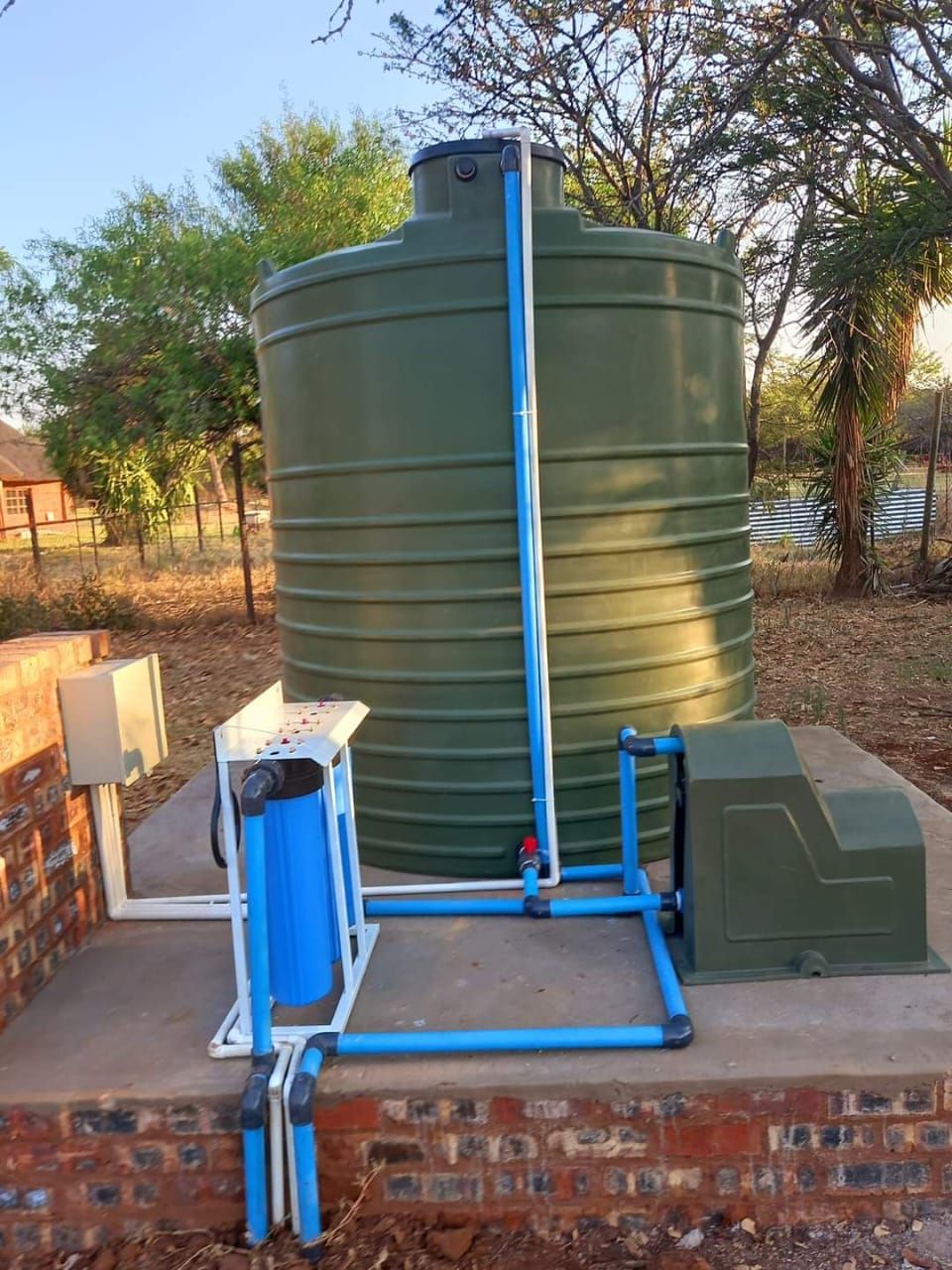 A green water tank with blue pipes attached to it.