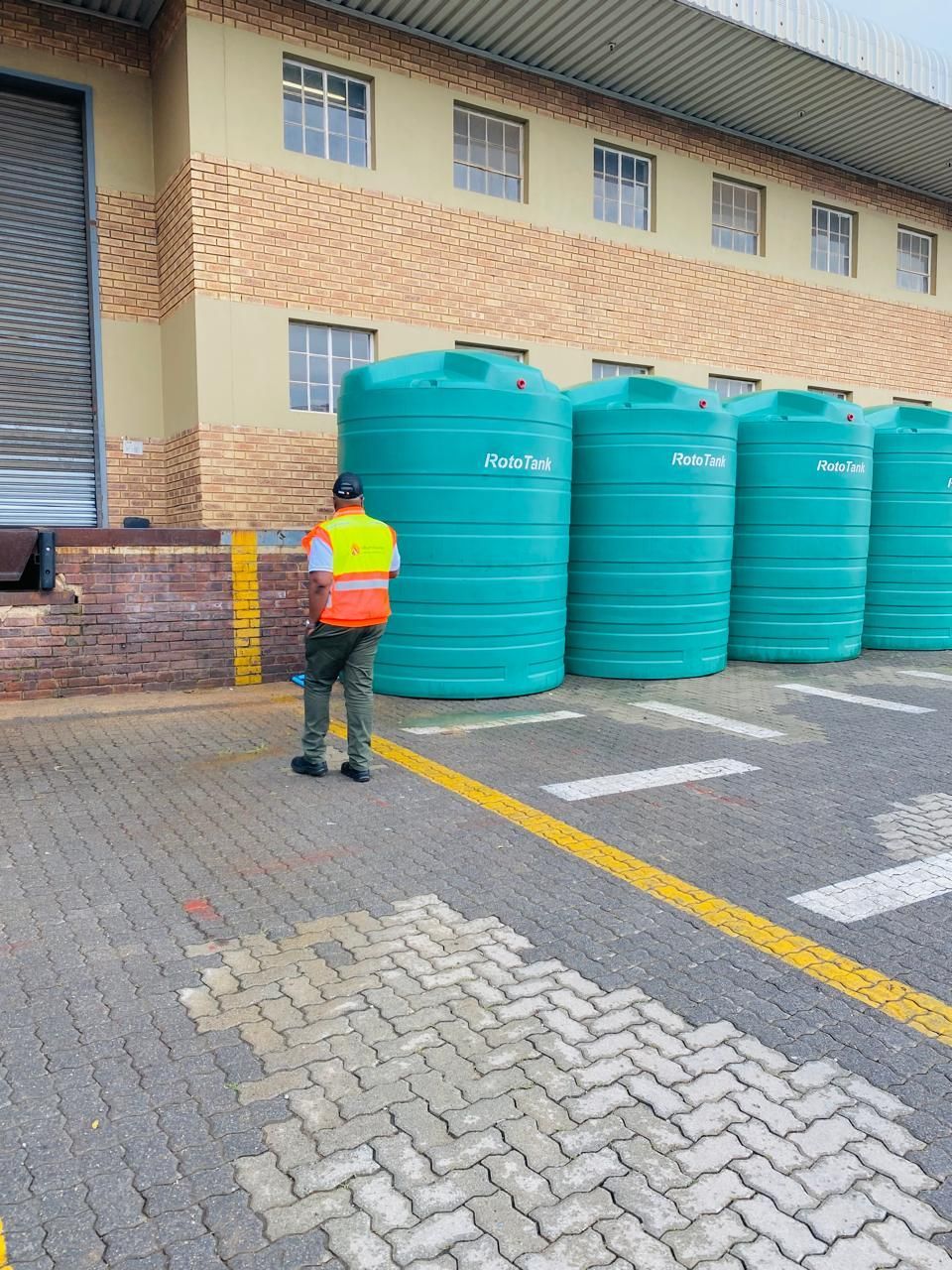 A blue water tank is being filled with water from a pipe.