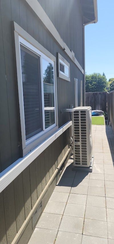 Exterior of a house with an air conditioning unit next to a window on a paved patio.