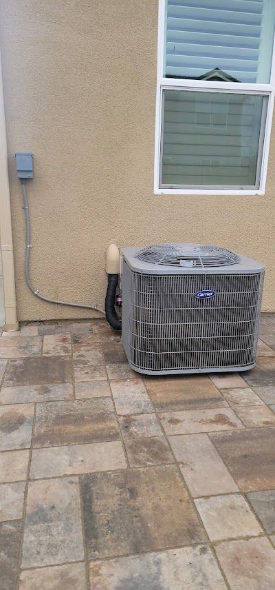 Air conditioning unit outside a building with stone pavers.
