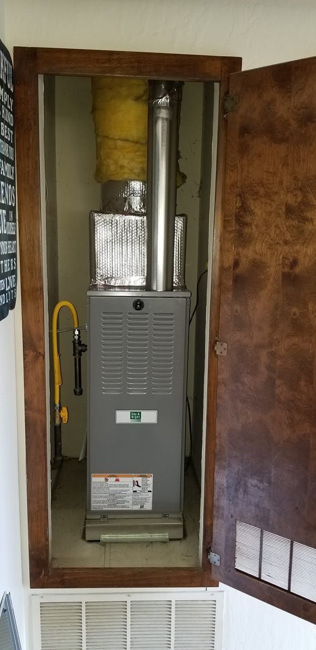A gas furnace inside a wooden cabinet with the door open, a yellow gas line is visible.