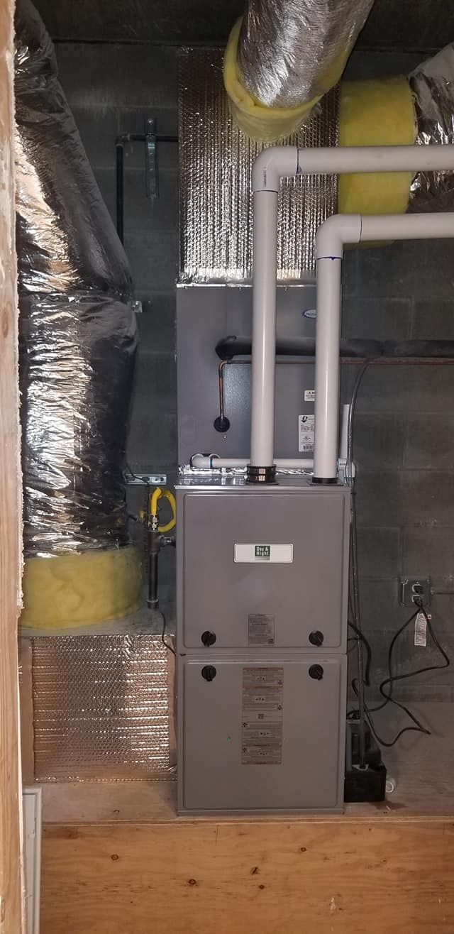 A gray furnace with ductwork in a basement setting.