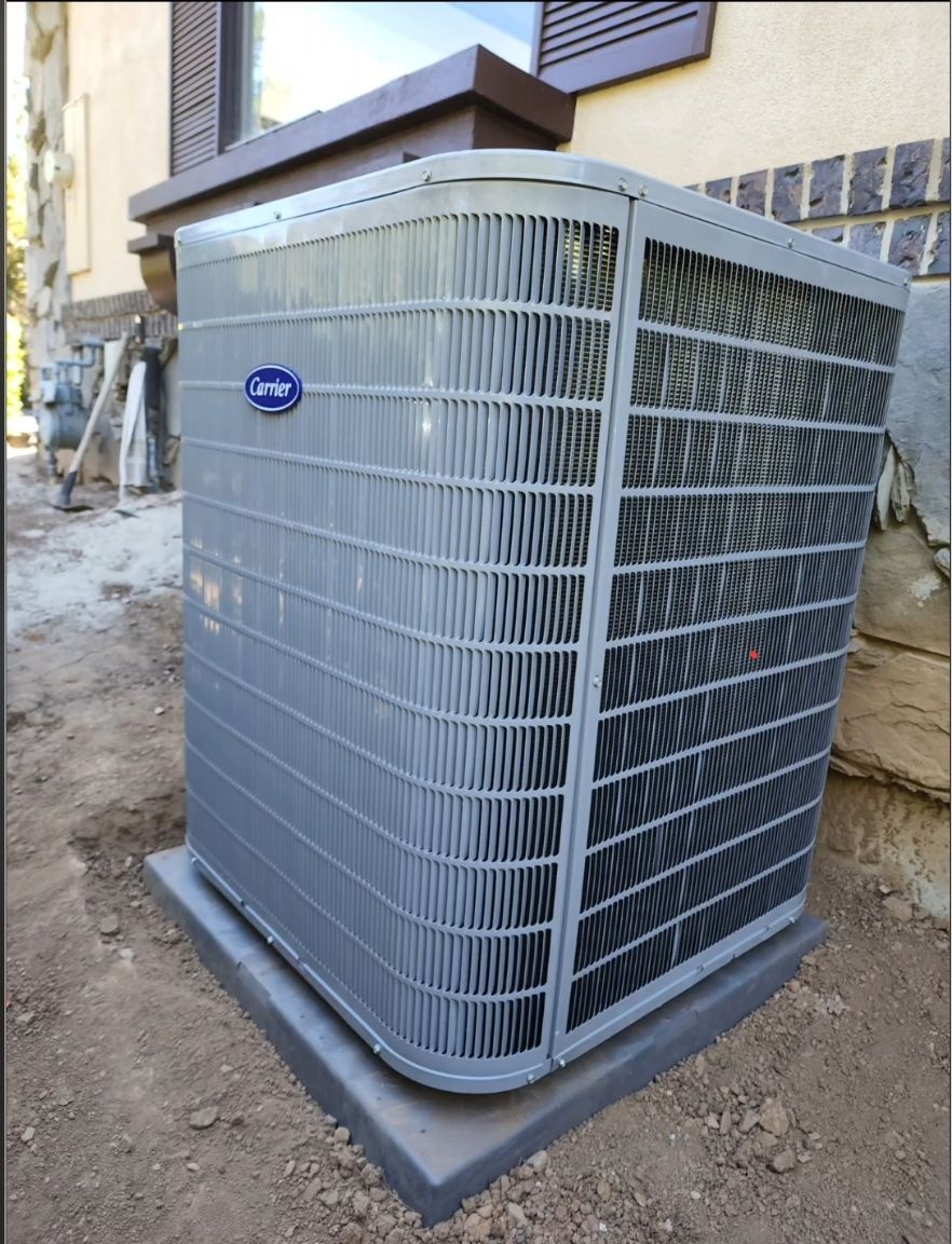 Gray Carrier air conditioning unit outside a building, on a concrete pad.