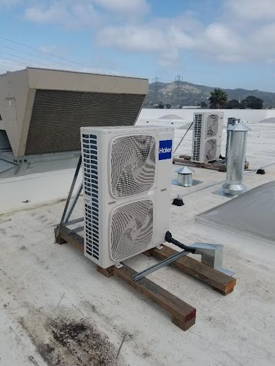 Air conditioning units on a white rooftop under a cloudy sky.