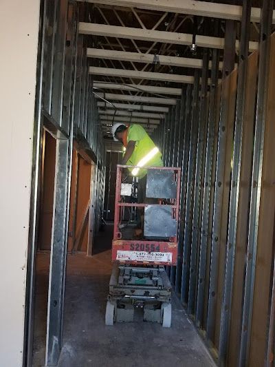 Construction worker on a lift in a hallway, working on the ceiling. Steel framing is visible.