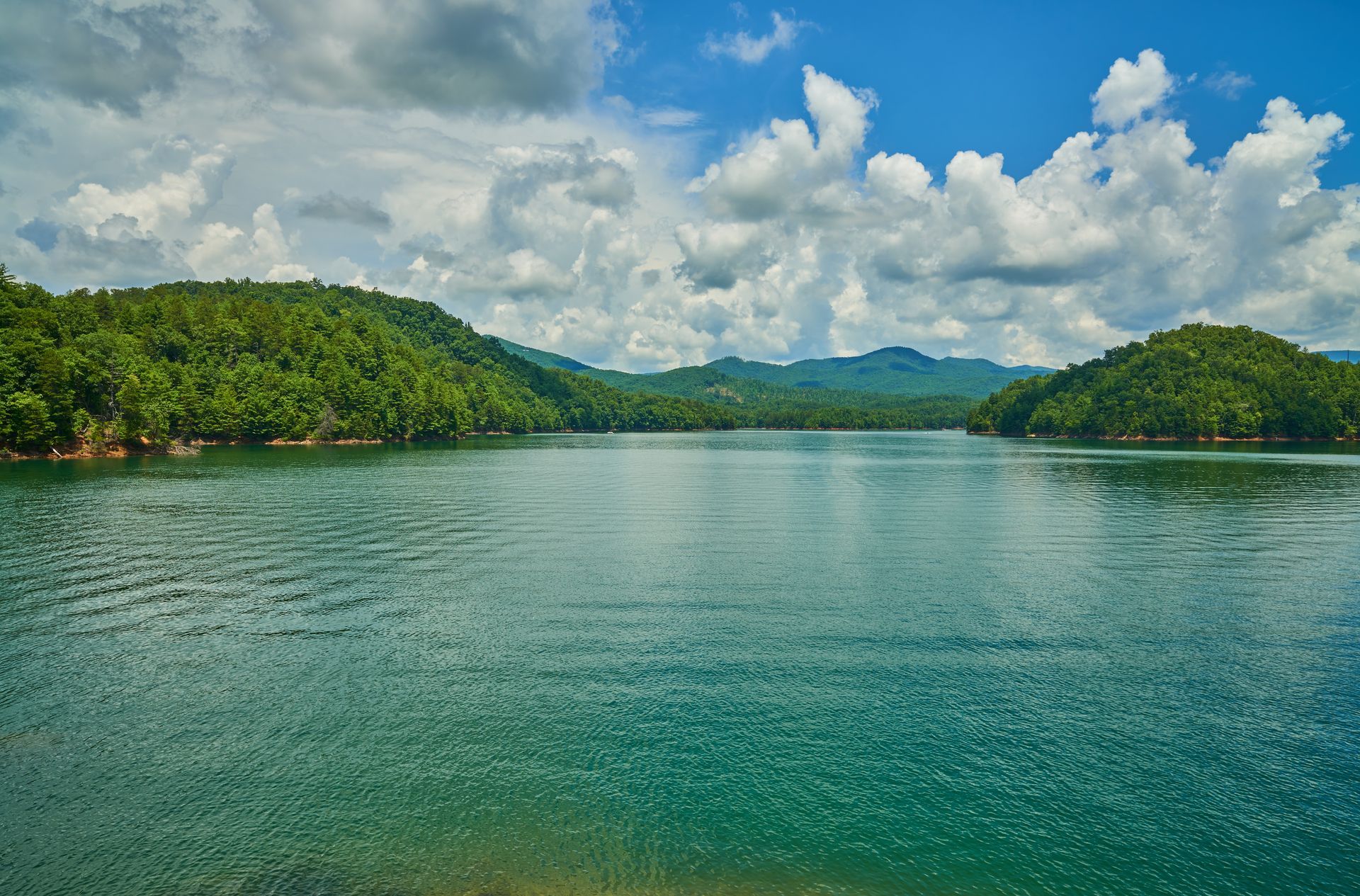 A large body of water surrounded by mountains on a cloudy day.