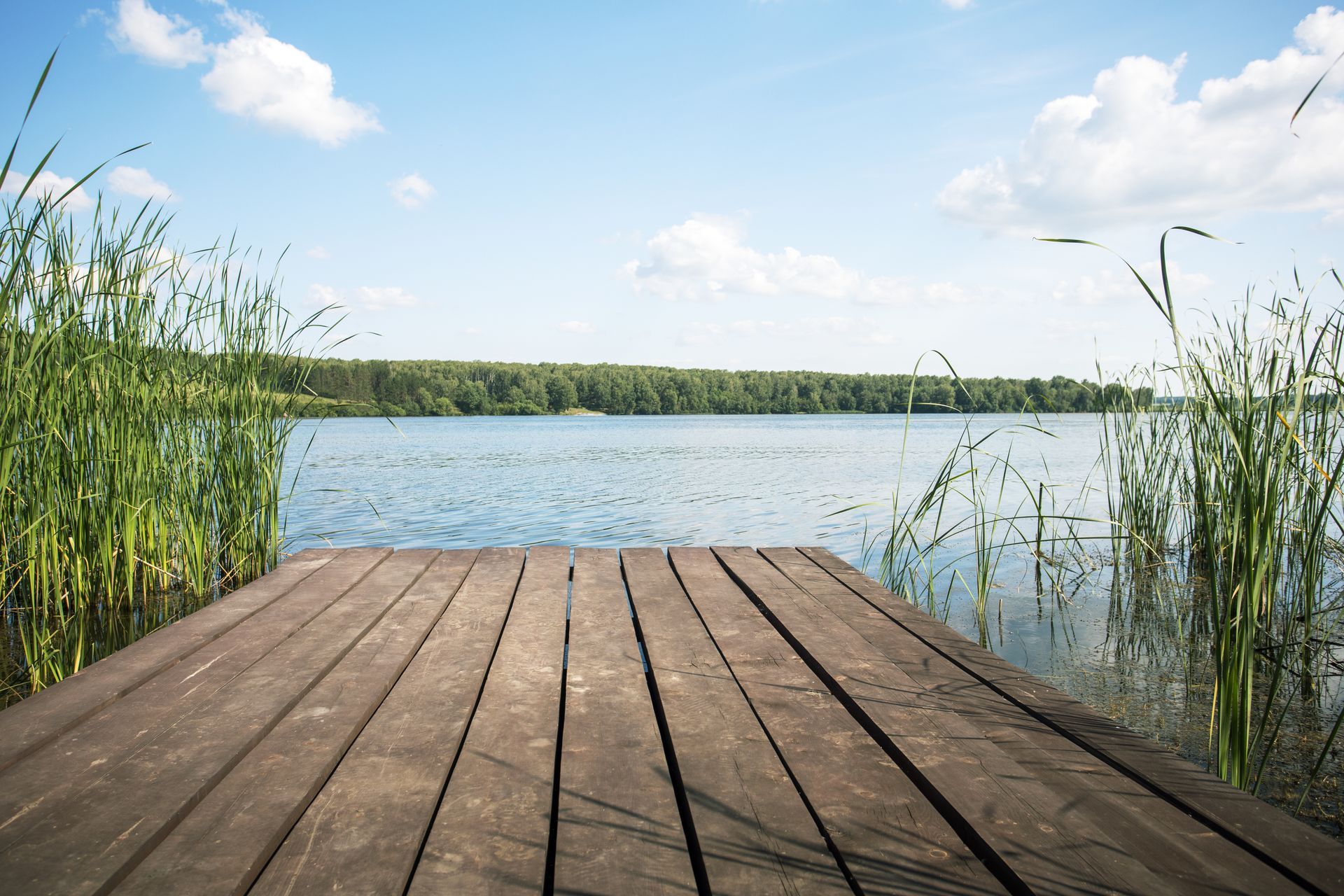 A park bench is sitting on a dock overlooking a lake.