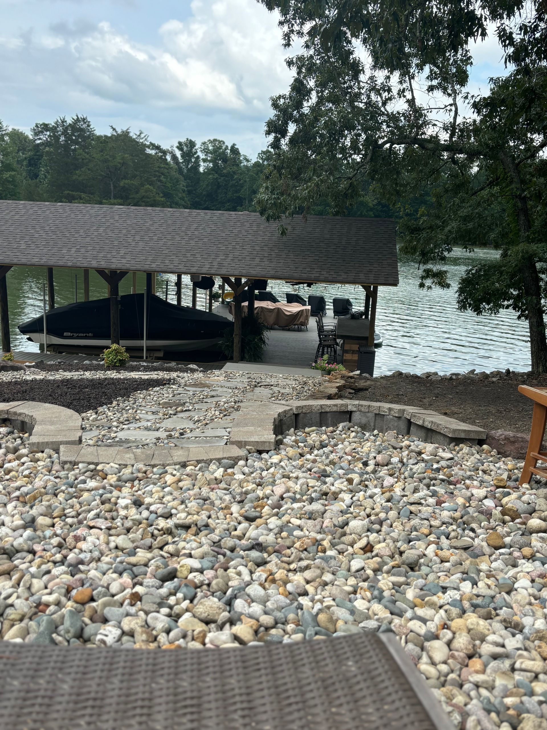 A boat is docked under a covered area near a lake