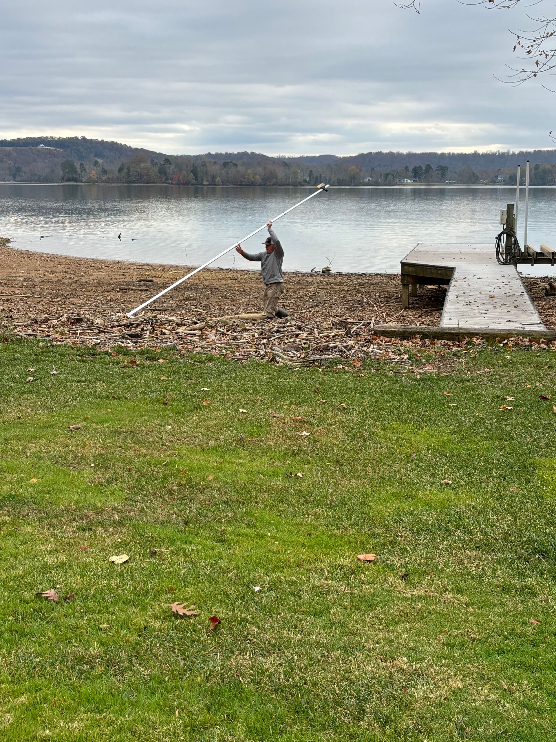 A person is standing on the shore of a lake holding a fishing rod.