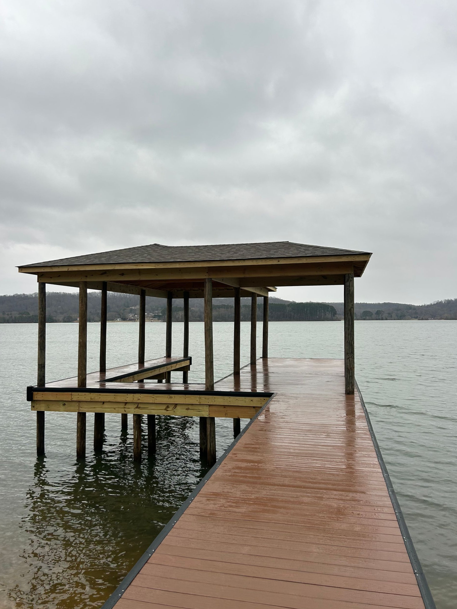Covered dock extending into a calm lake under an overcast sky
