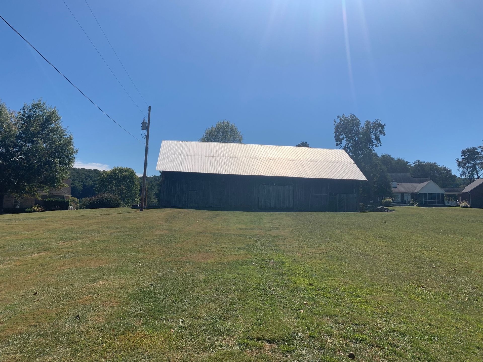 A large barn is sitting in the middle of a grassy field.