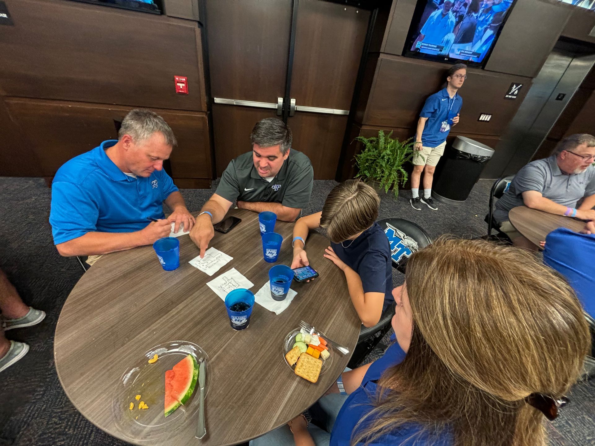 A group of people are sitting around a table with drinks and food.