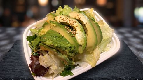Avocado-topped salad wrap with greens on a white plate