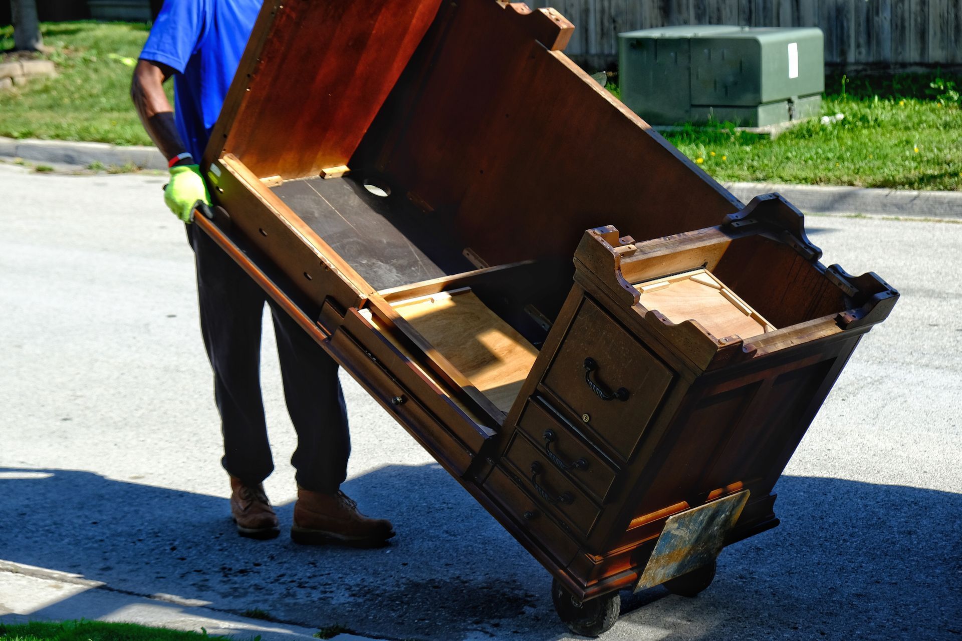 A man is carrying a large piece of wood on a cart