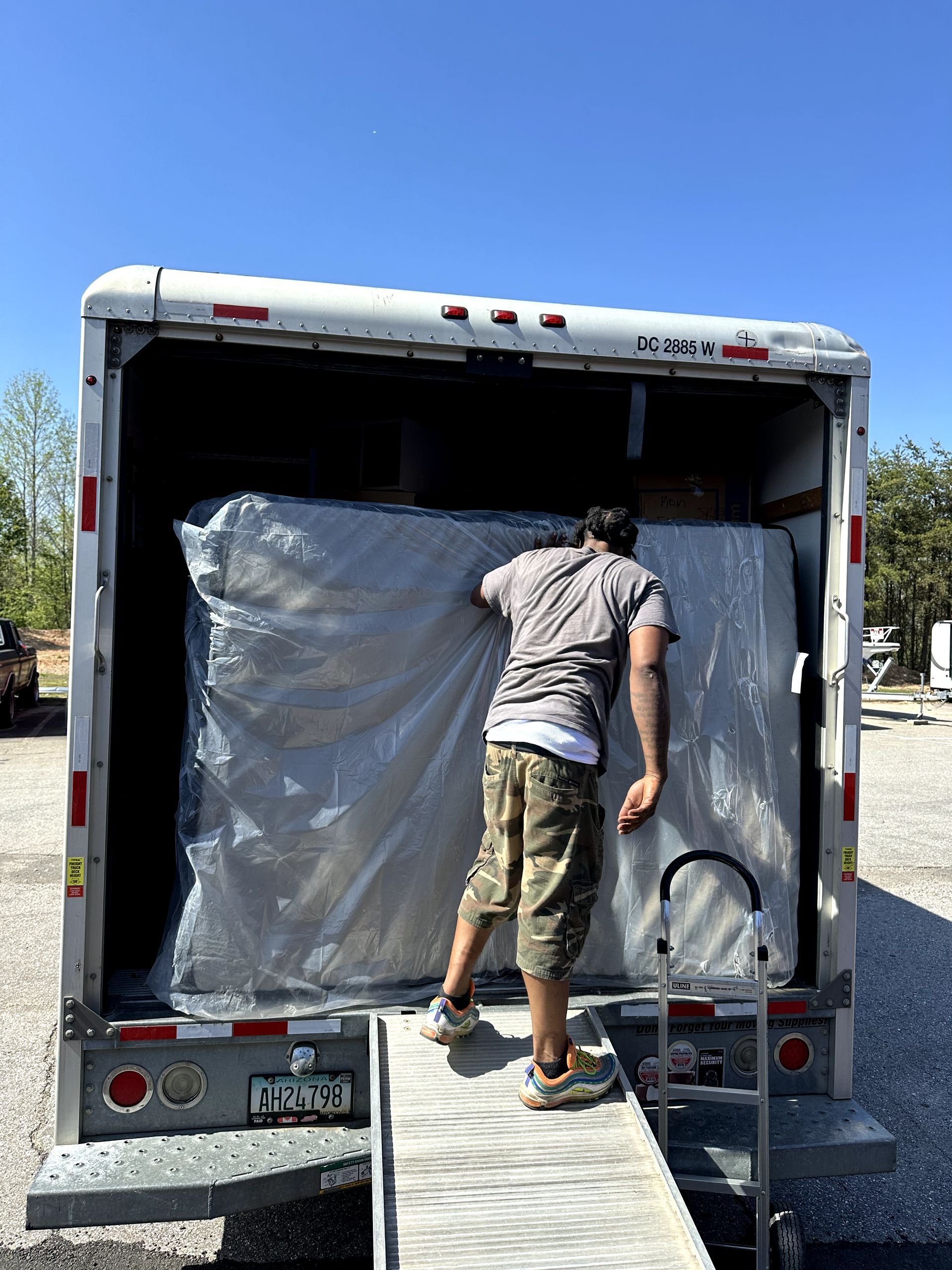 A man is loading a mattress into the back of a truck.