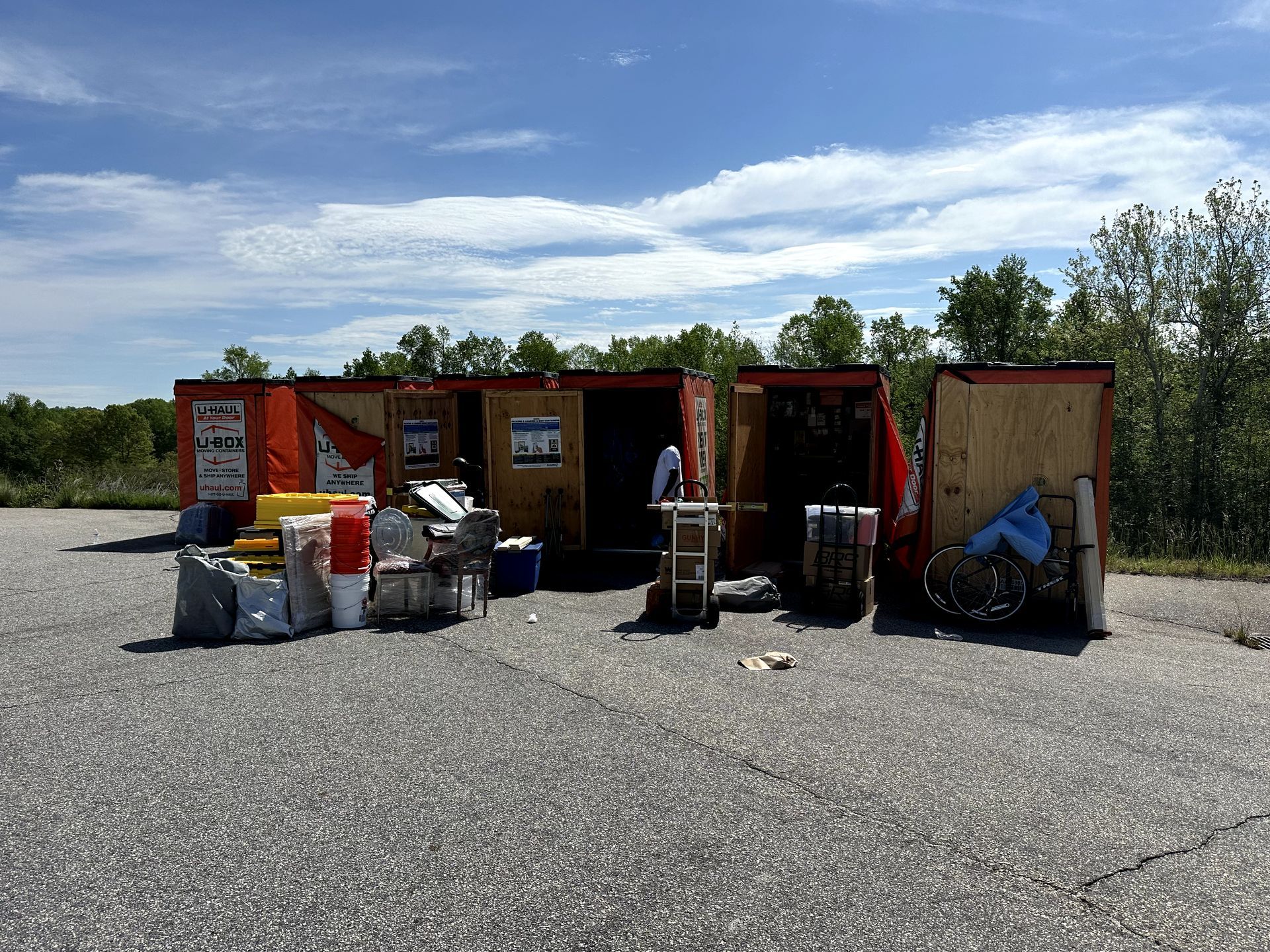 A group of red containers sitting on top of a gravel road.