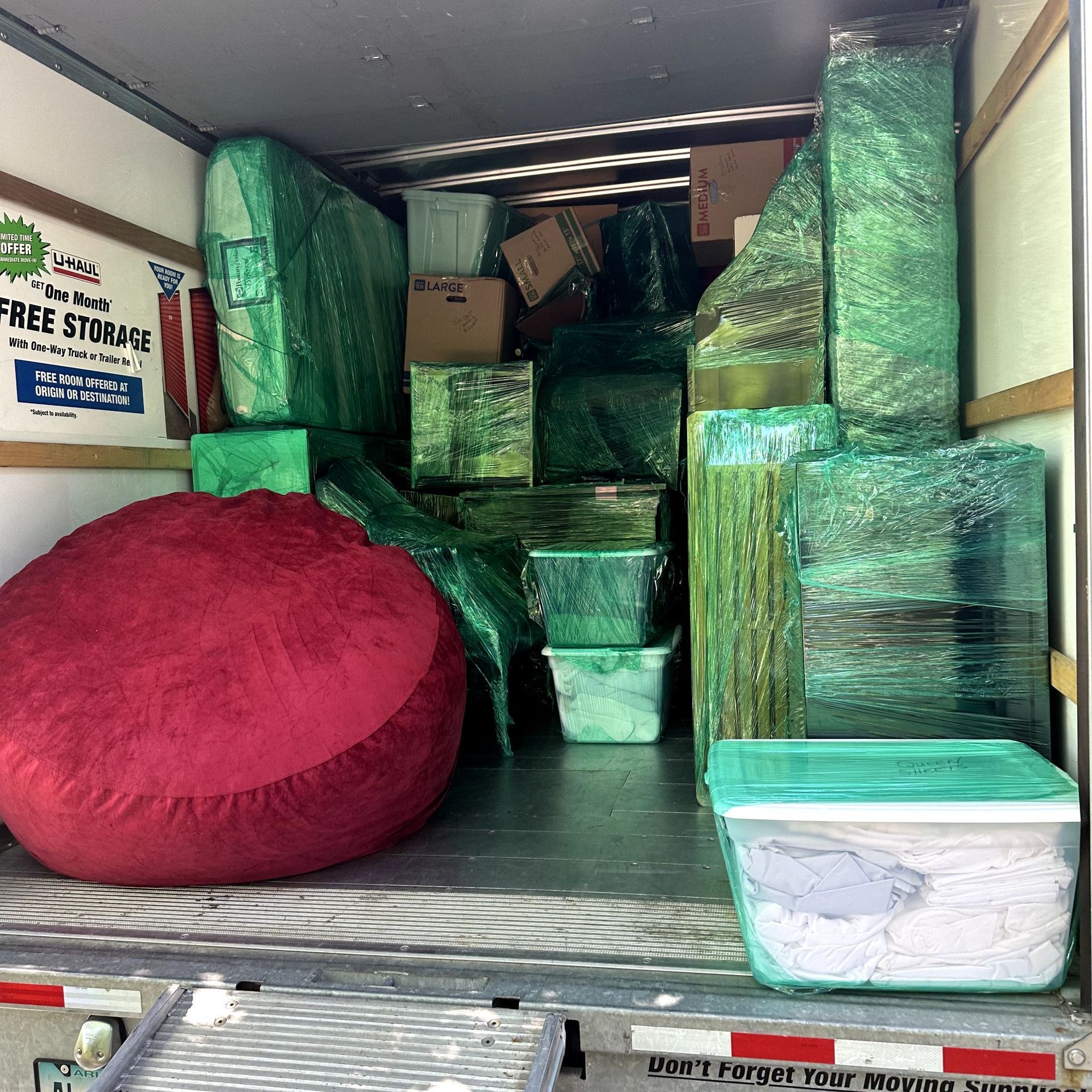 The back of a moving truck filled with boxes and a bean bag chair.