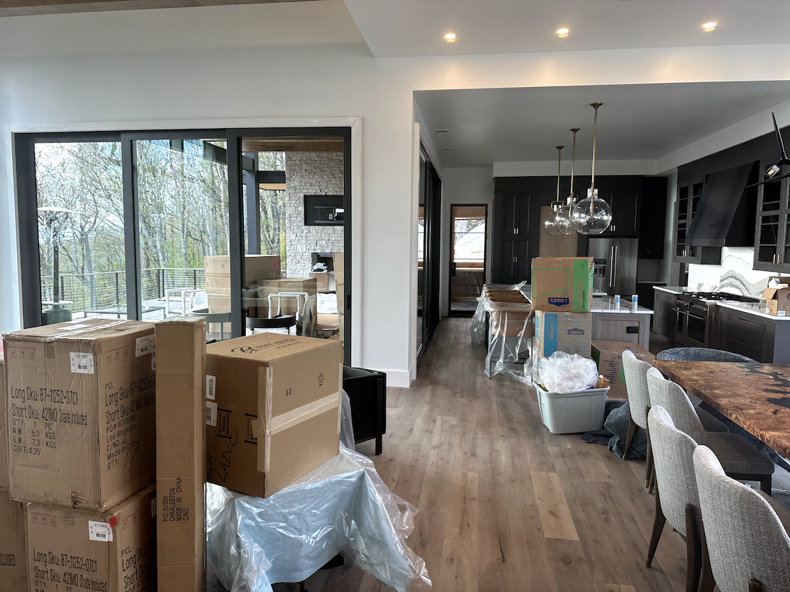 A kitchen and dining room in a house under construction with boxes stacked on top of each other.
