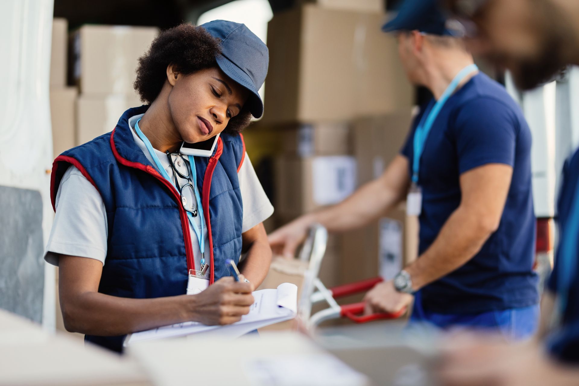 A woman is sitting at a table in a warehouse writing on a piece of paper.