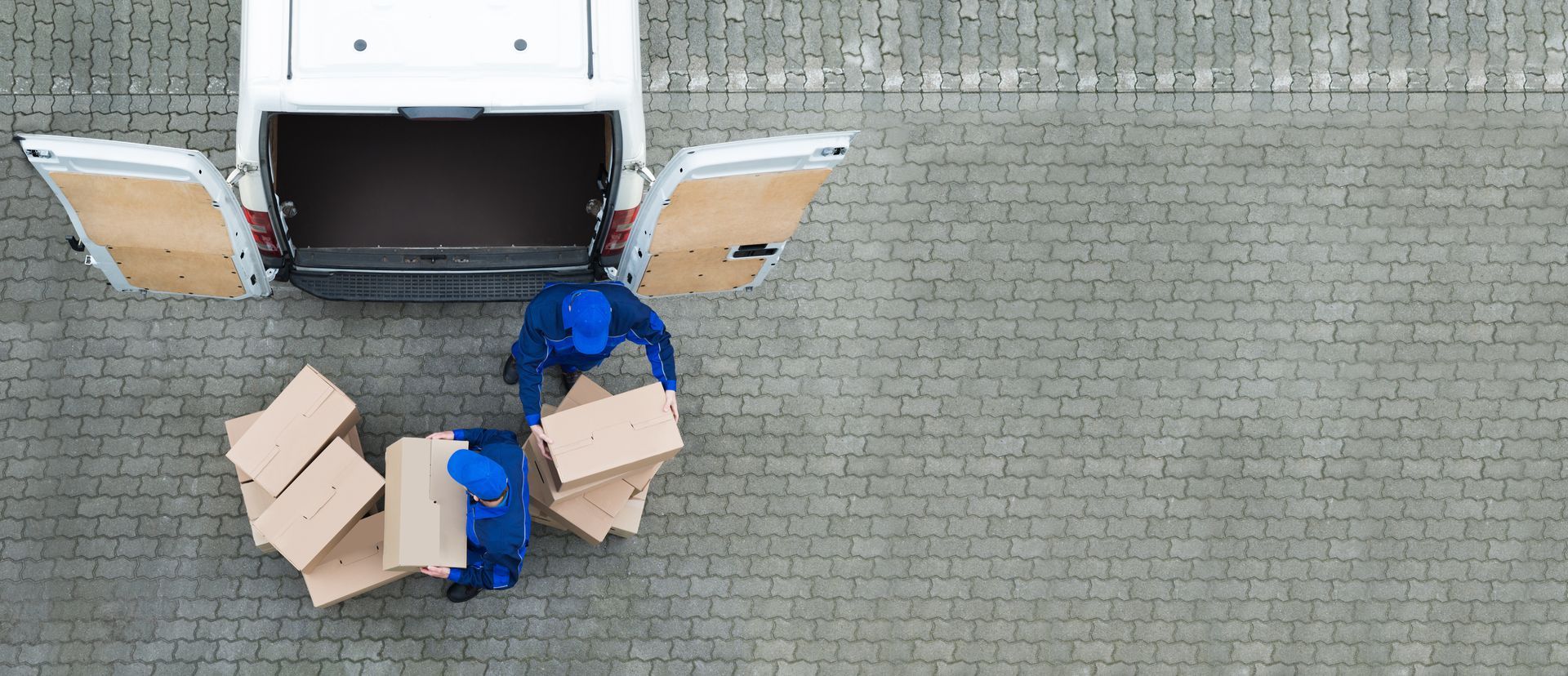 An aerial view of two delivery men loading boxes into a van.